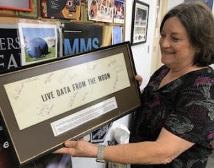Patricia Reiff displays a sign that hung above the NASA control room where scientists monitored lunar experiments. The sign is autographed by those present when the experiments were shut down in September 1977.