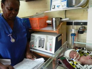 A nurse monitors a baby that is receiving CPAP treatment