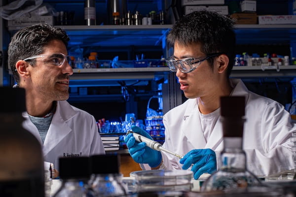 Rafael Verduzco, left, a chemical and biomolecular engineer at Rice University, and graduate student Hao Mei led a study that shows microscopic bottlebrush polymers are drawn to the top and bottom of a coating applied to a surface. The discovery could lead to a way to customize the properties of coatings for specific applications. (Credit: Jeff Fitlow/Rice University)