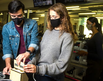 Rice University engineering students have designed a low-cost touchless temperature monitor. Diego Gonzalez and Caterina Grasso Goebel make an adjustment to the temperature readout, attached by a long cable to the sensor to keep people at a distance. (Credit: Photo by Jeff Fitlow/Rice University)