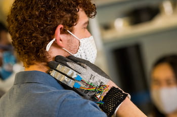 Rice University engineering student Zach Alvear tests the prototype glove developed to monitor the hand motions of people with trichotillomania, the compulsive pulling of hair, to help them modify their behavior. (Credit: Photos by Jeff Fitlow/Rice University)